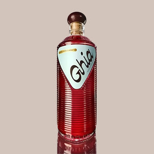 Bottle of Ghia non-alcoholic aperitif featuring a ribbed red glass design, light blue label, and round wooden cap, displayed against a white background.