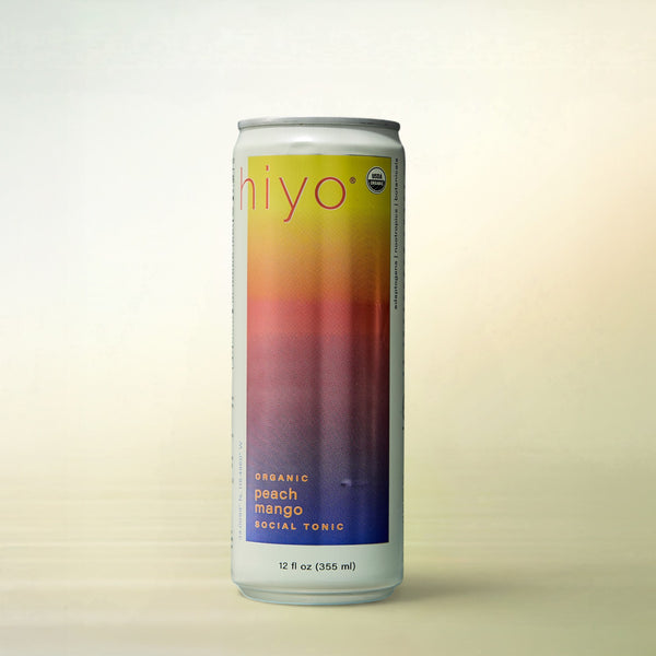 hiyo Peach Mango Seltzer, alcohol-free functional wellness beverage, can on a soft gradient background