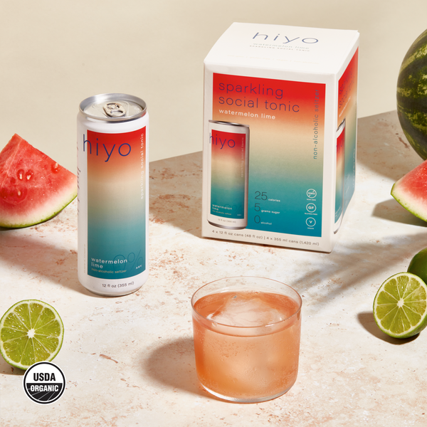 hiyo Watermelon Lime alcohol-free seltzer can, four-pack box, and glass over ice with fresh watermelon and lime